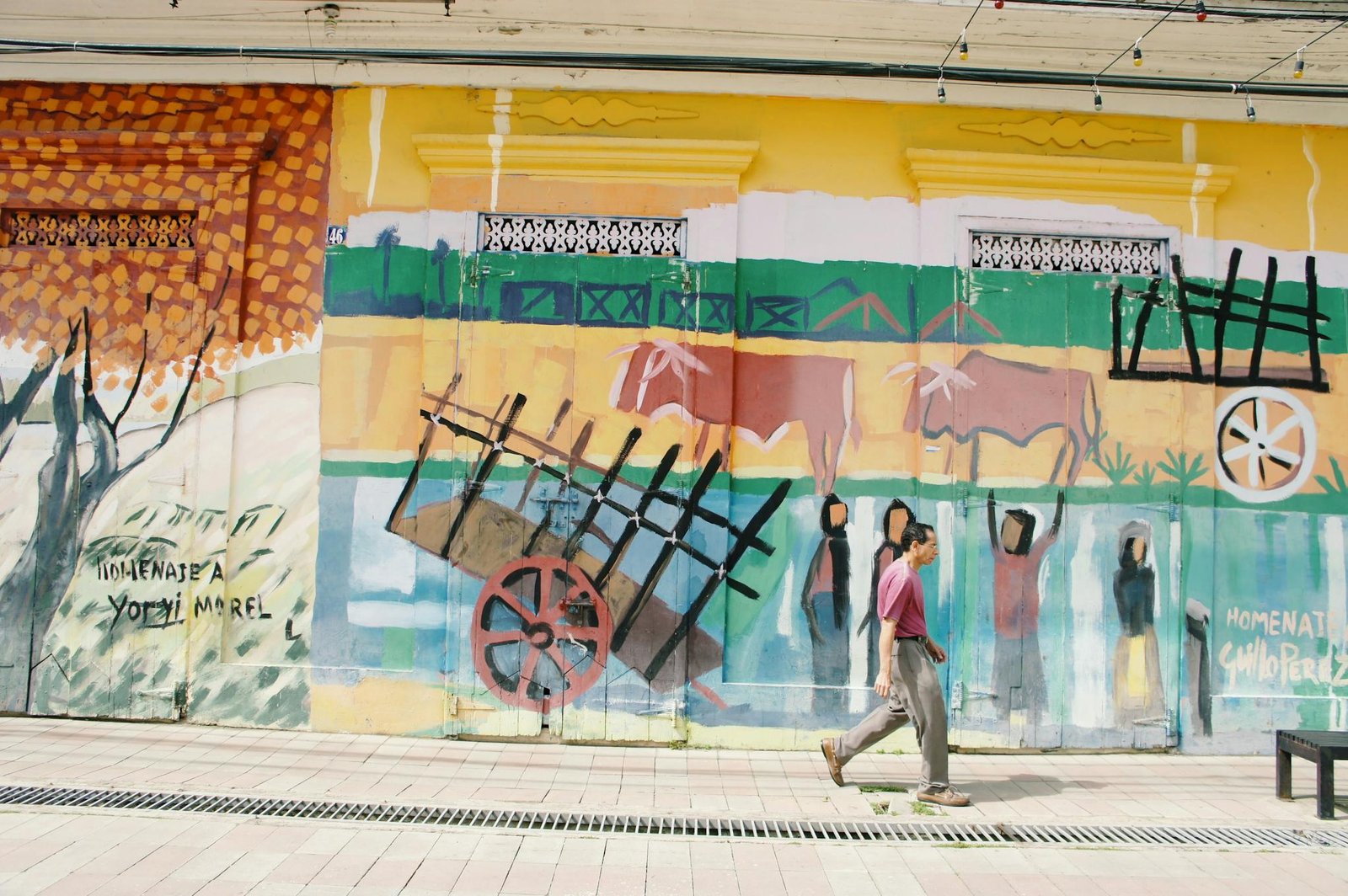A vibrant street mural in Santiago, depicting cultural themes with an individual walking past.